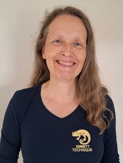 Eine lächelnde Frau in einem schwarzen Shirt mit Emblem "Emmett Technique".