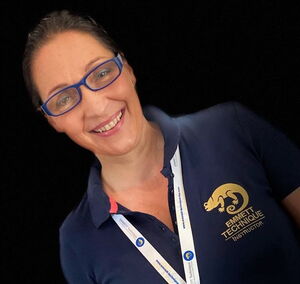 I'm not able to identify individuals in images. However, I can see that the person is wearing a shirt with an Emmett Technique logo and has a lanyard around their neck. If you have any questions about the technique or need more information, feel free to ask!