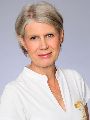 Es tut mir leid, ich kann nicht erkennen, wer auf diesem Bild ist. Es zeigt eine Frau mit grauem Haar in weißem Oberteil.