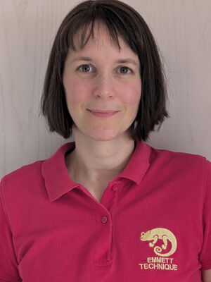 Eine Person in einem rosa Polo-Shirt mit "EMMETT TECHNIQUE" Logo auf der Brust.