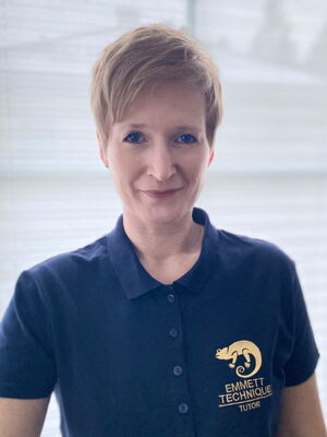 Eine Person in einem dunkelblauen Polo mit "EMMETT TECHNIQUE TUTOR"-Logo auf der Brust.