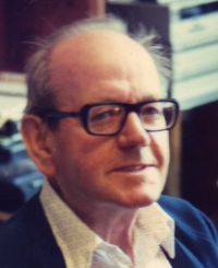 Es ist ein älterer Mann mit Brille und Hemd.